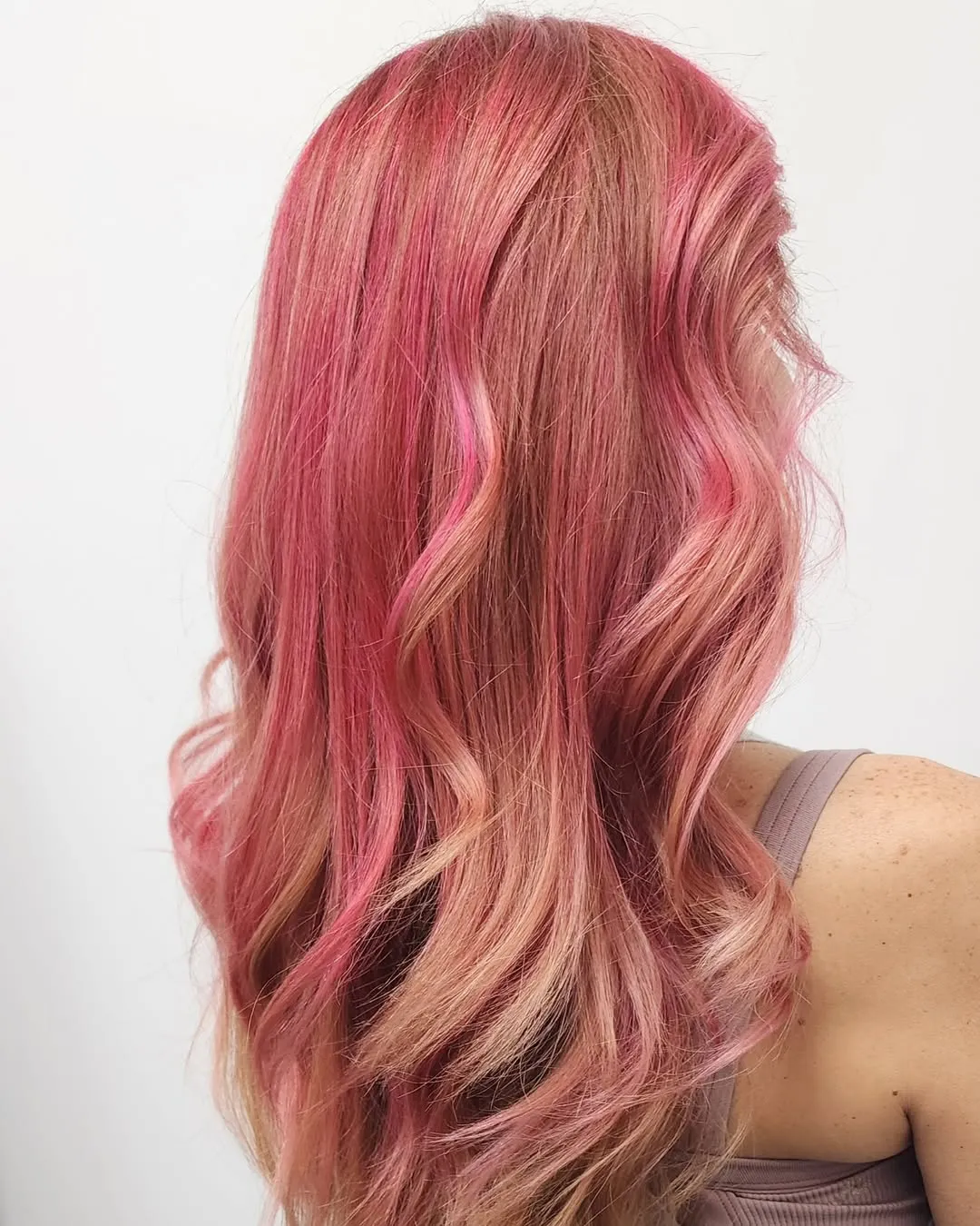 Rose-pink and blonde balayage on long waves, seen from behind